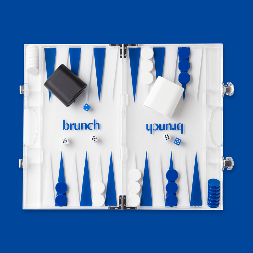 Top view of Brunch acrylic backgammon set with blue and white points, checkers, dice, and clear case on blue background