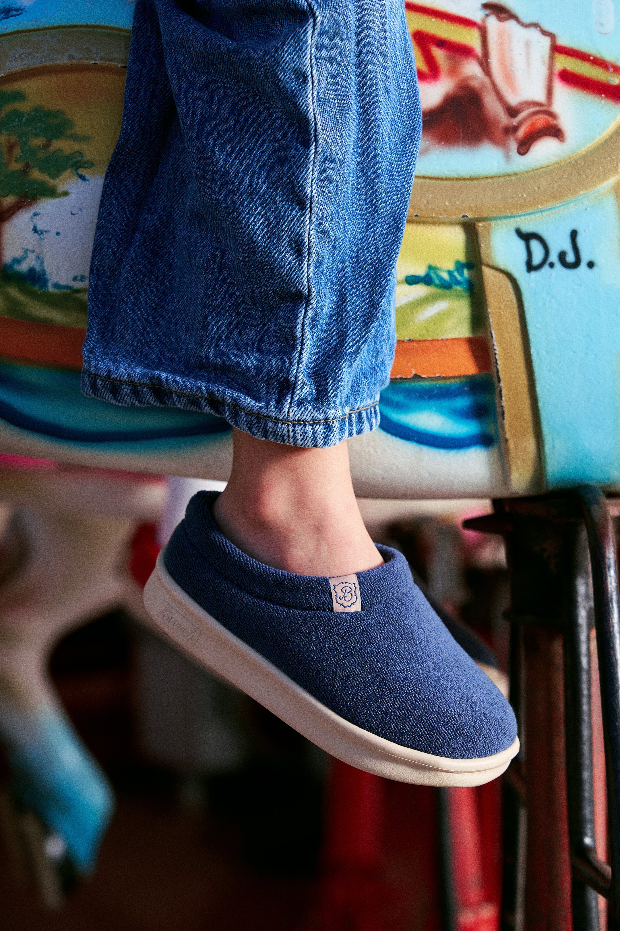 Child's foot wearing blue slip-on and jeans resting on painted carousel horse panel signed 'D.J.'