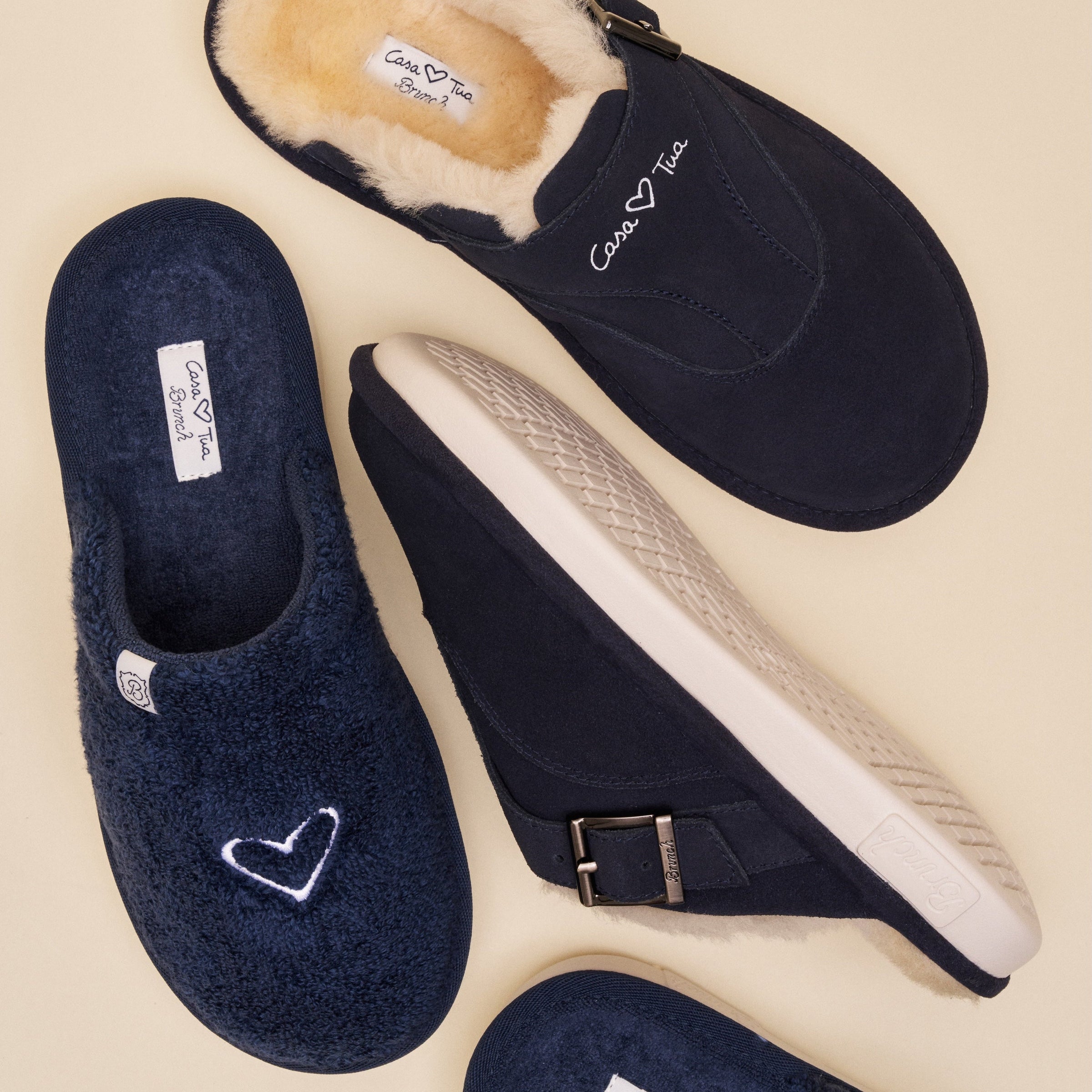Navy shearling-lined house slippers arranged overhead, one with embroidered 'Casa Tua' logo