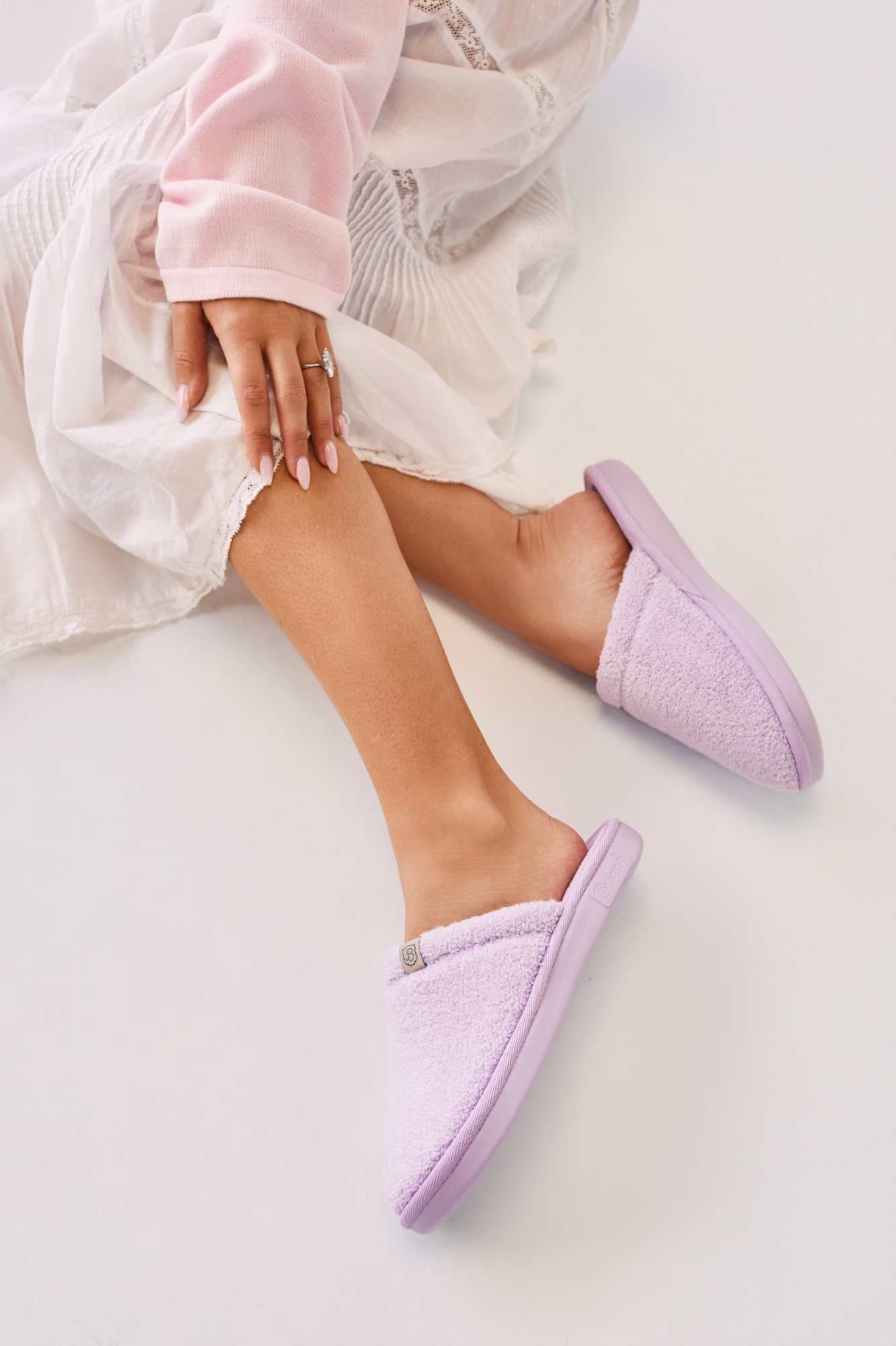 Person wearing light purple slippers on a white surface