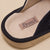 Charcoal suede slipper close-up with stitched label "Brunch" and embossed "brunch" on the sole