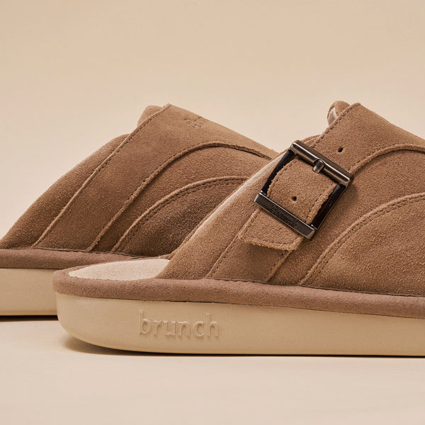 Suede slip-on sandal with metal buckle and embossed 'brunch' logo on sole, warm tan color