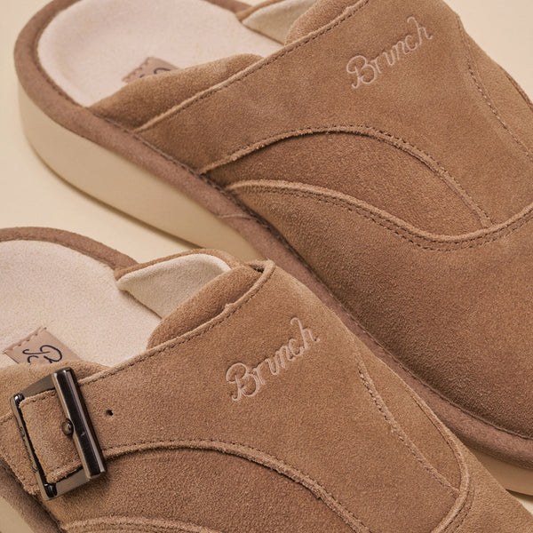 Tan suede slip-on mule with embroidered 'Brunch' on the upper and metal buckle