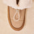 Top of camel shearling-lined slipper showing suede trim, textured leather upper and gold cord toggle