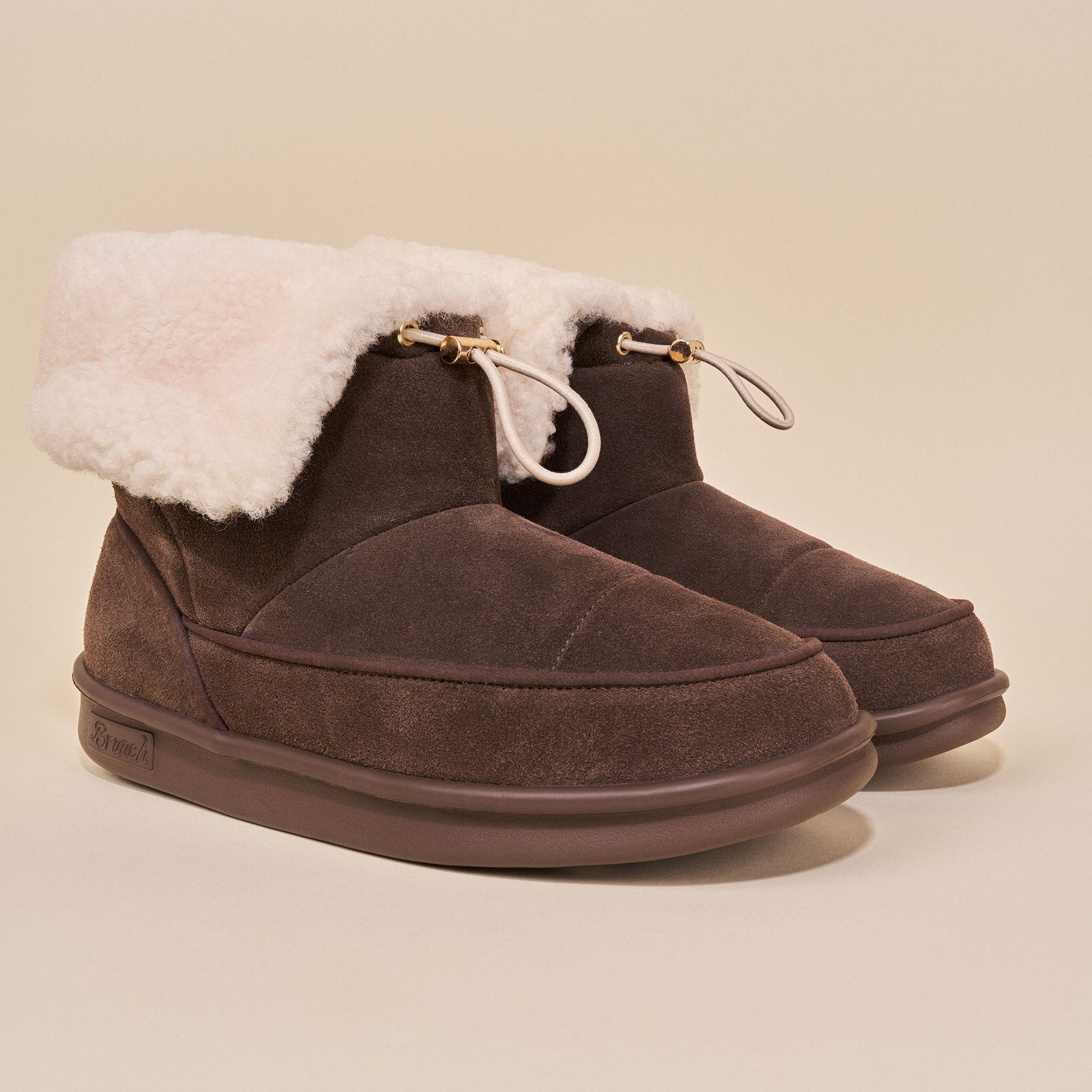 Suede ankle slippers with shearling cuff and gold-tipped drawcord, dark brown.