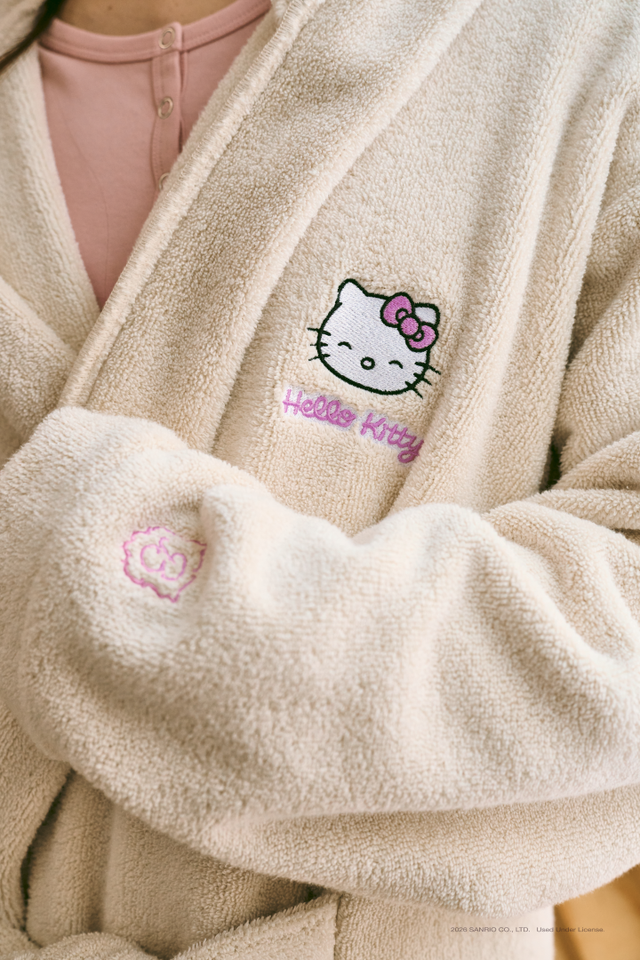 Beige fleece robe with Hello Kitty embroidery; small print: 2026 SANRIO CO., LTD. Used Under License.