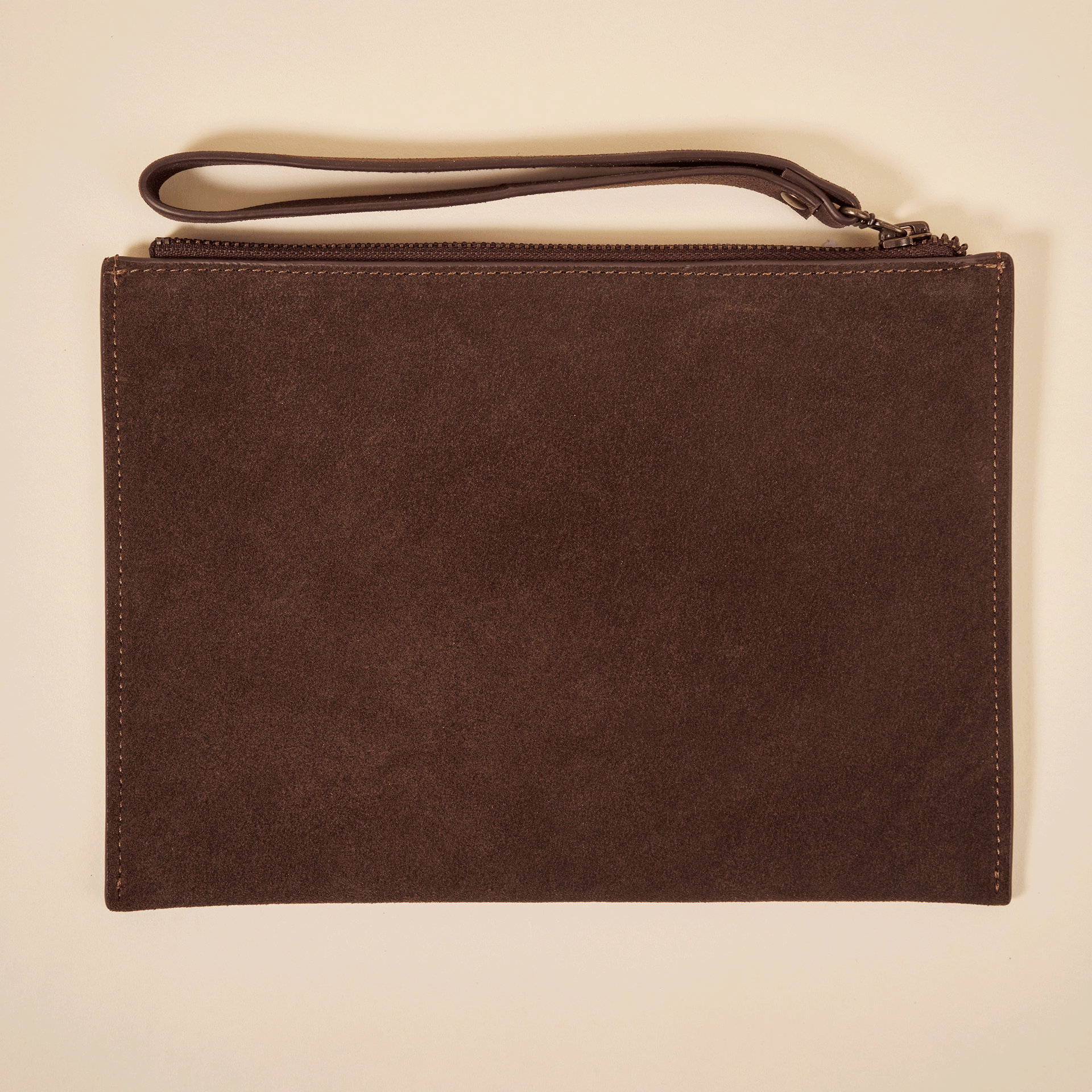 Brown suede wristlet clutch with zipper and leather wrist strap, photographed flat on a light background.