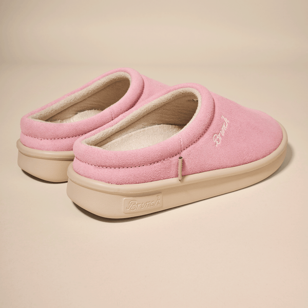 Pink suede slip-on slippers with cream sole and fleece lining, "Brunch" brand embossed on sole and embroidered on top.