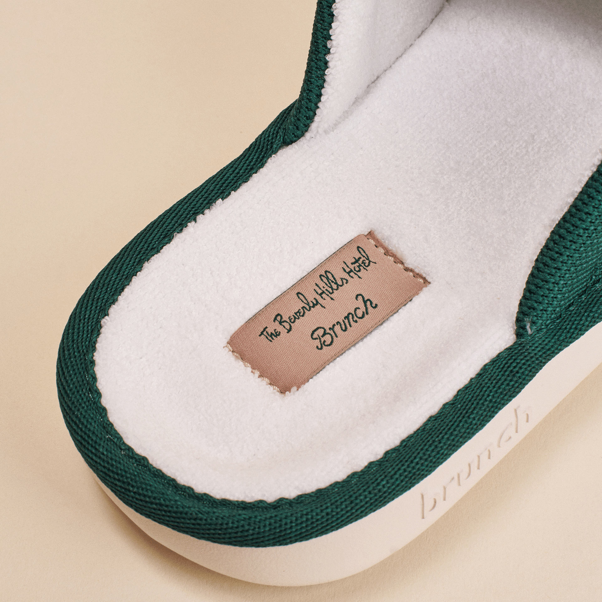 Green-trim slipper insole with stitched label 'The Beverly Hills Hotel' and tag reading 'Brunch', embossed side text 'brunch'