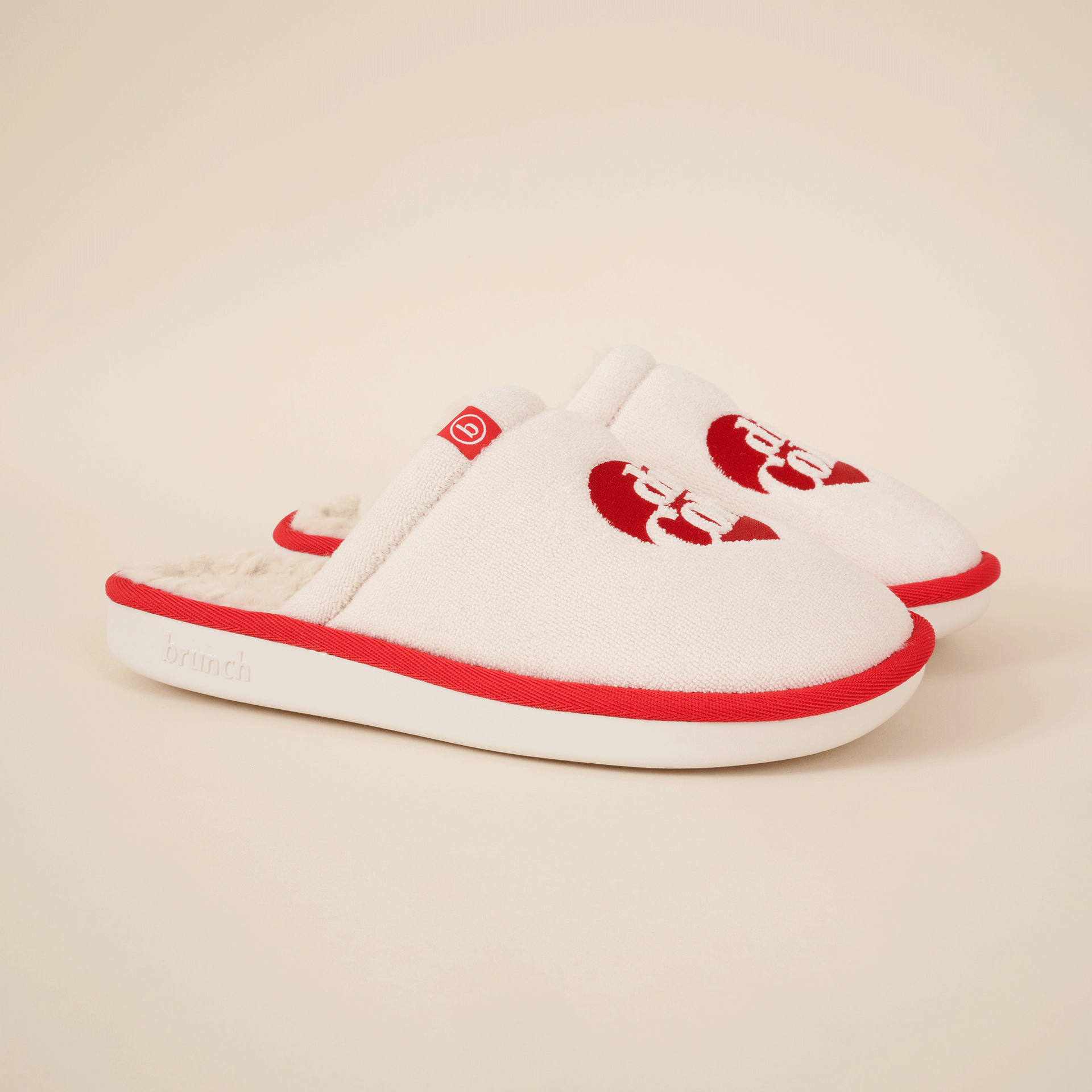 Cream terry slip-on slippers with red trim, red heart logo on top, small tag with 'b', and 'brunch' embossed on the sole