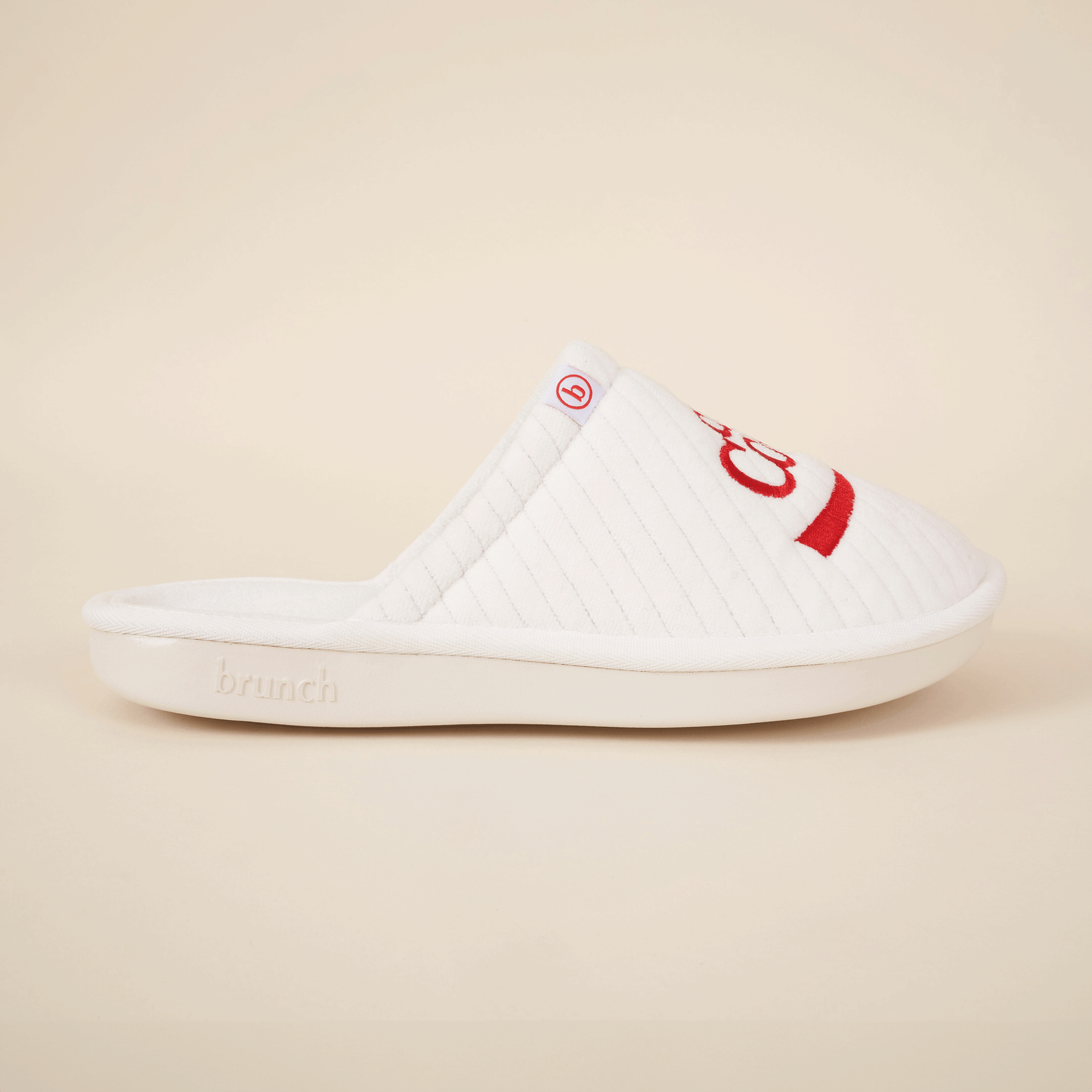 White quilted slip-on slipper with red embroidery, small b tag and brunch embossed on the sole