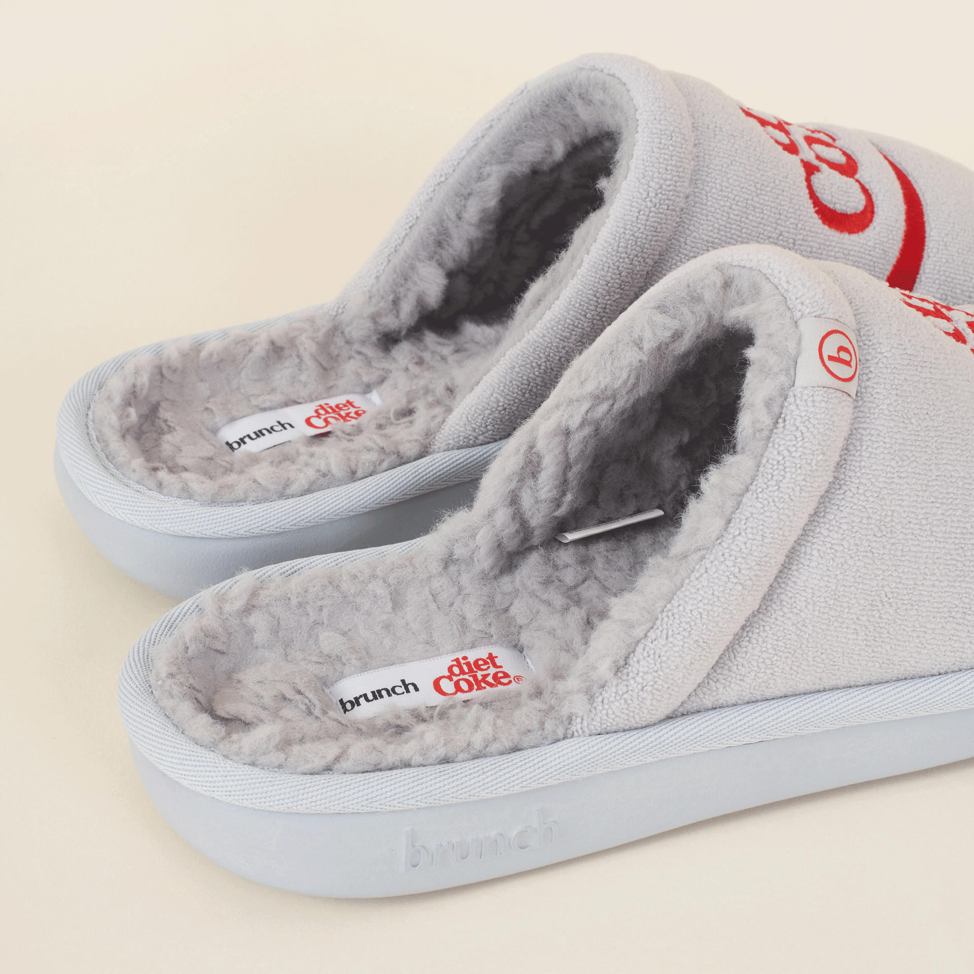 Grey fleece-lined slippers with 'brunch' and 'diet Coke' labels and small 'b' tag