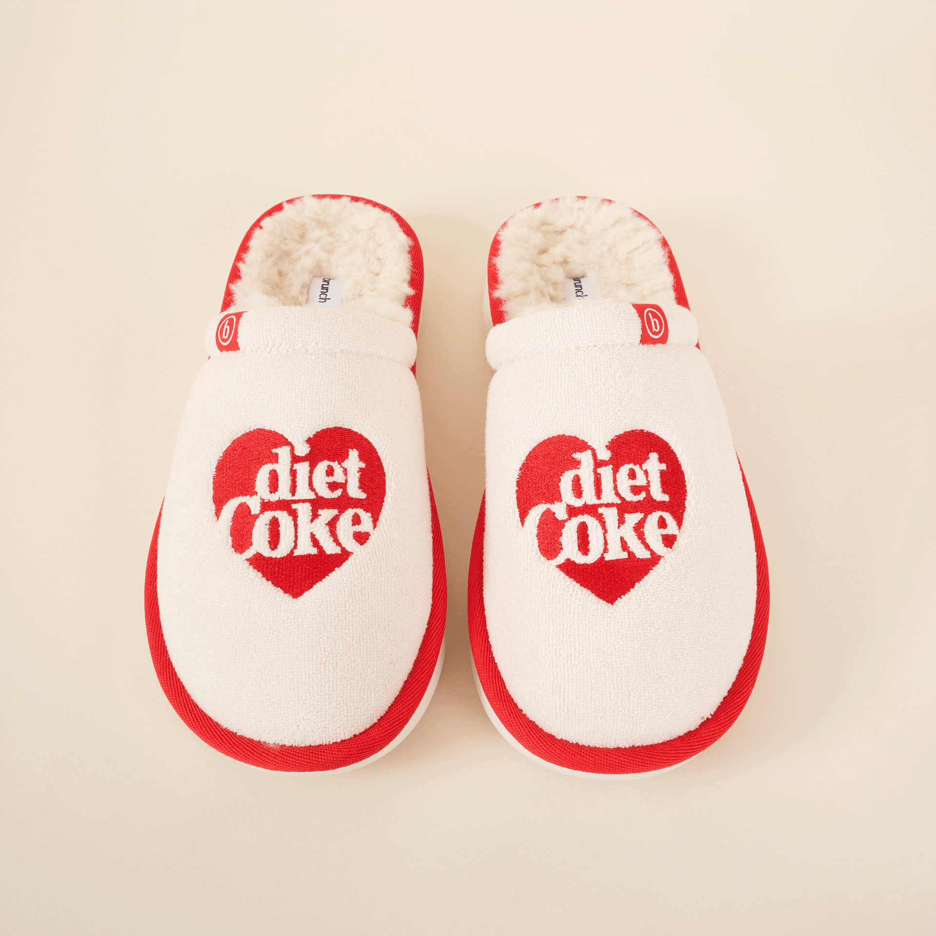 White-and-red fuzzy slippers with a red heart logo reading 'diet coke' on each toe