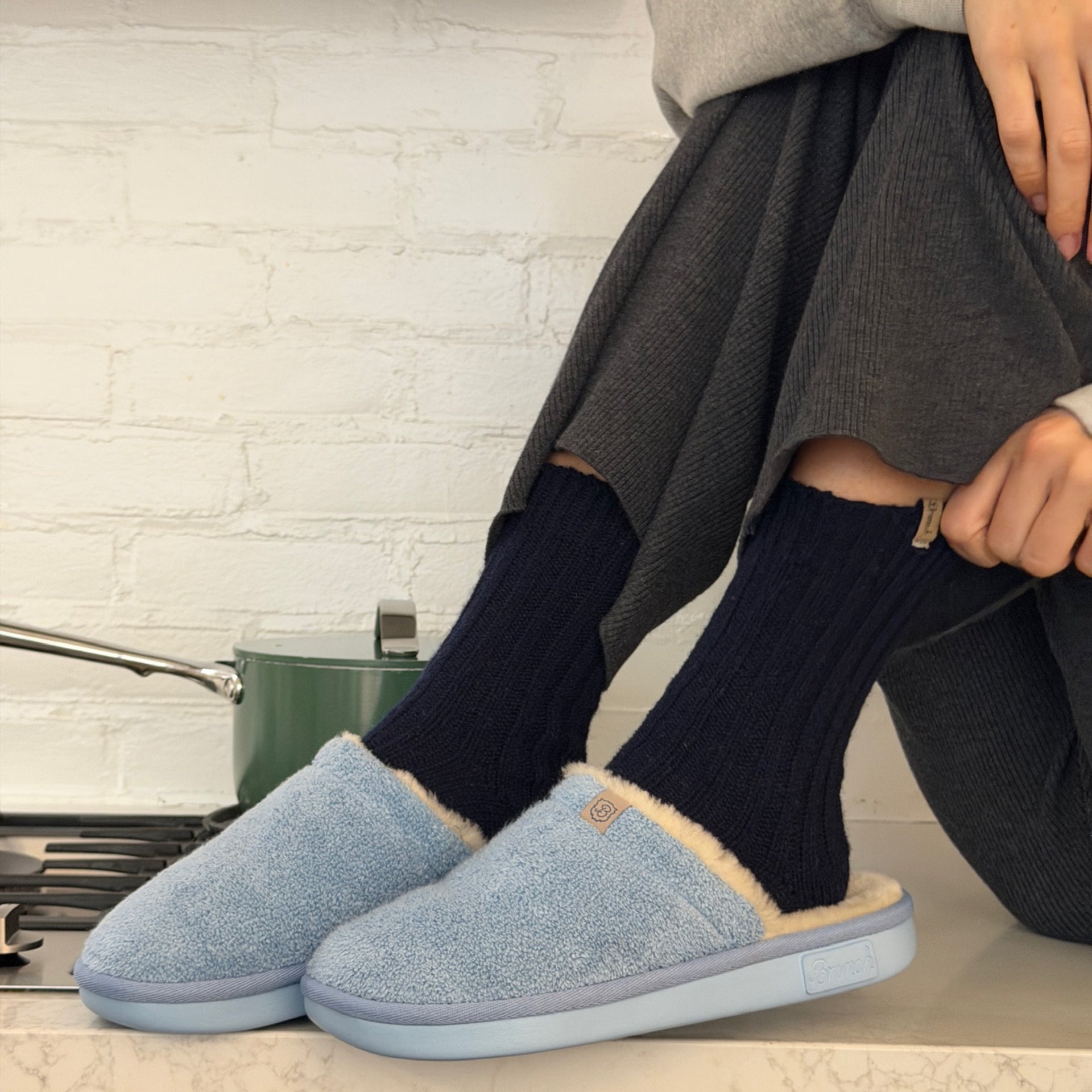 Person on counter wearing navy ribbed socks and light blue fuzzy slippers