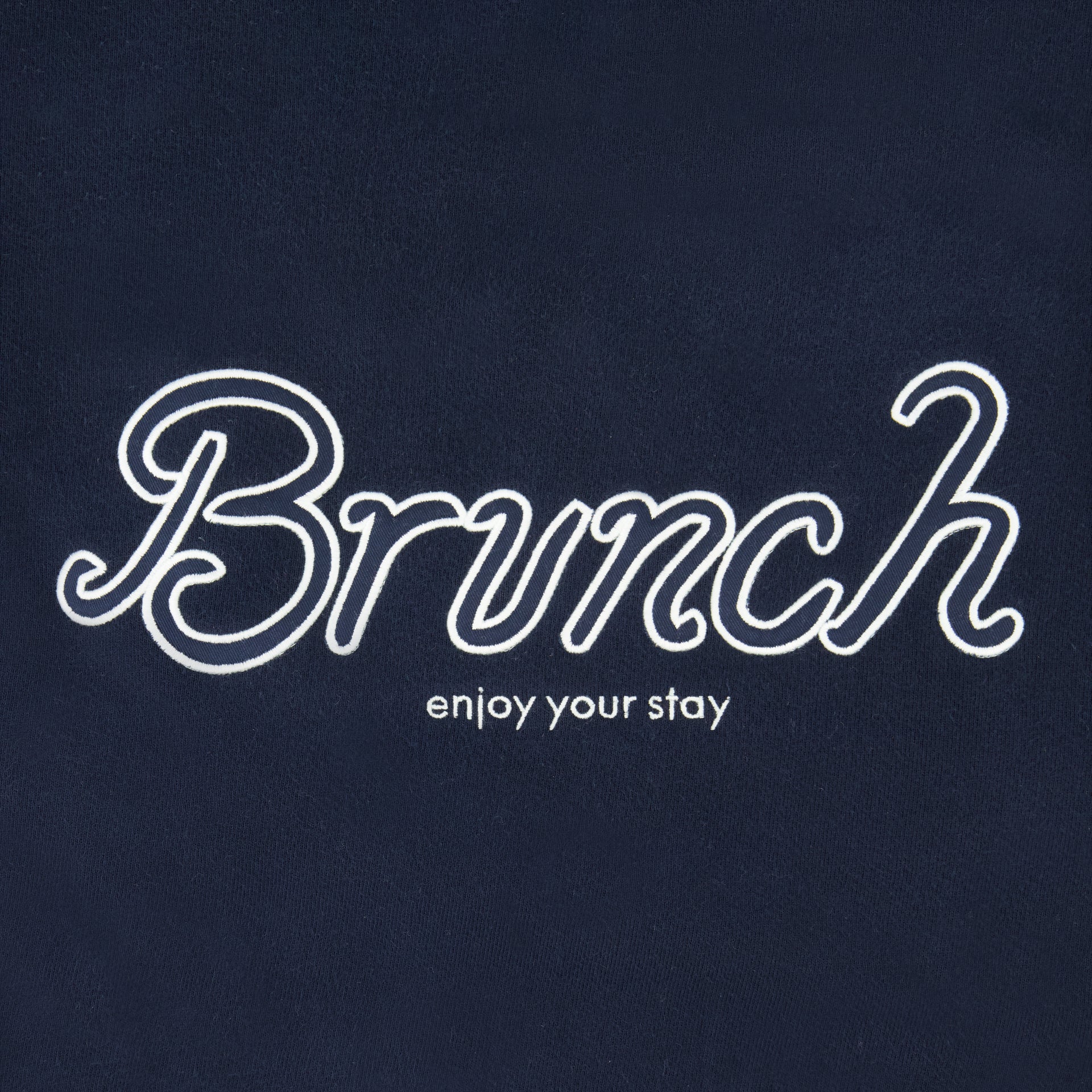 Brunch script lettering with 'enjoy your stay' embroidered on navy fabric.