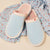 Light blue slip-on slippers with pink terry lining on blue fabric patterned with breakfast icons and repeated text 'Brunch' and 'zzz'