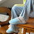 Light blue slip-on slippers labeled 'Brunch' worn with breakfast-print pajama pants showing 'zzz', seated on wooden chair and table.