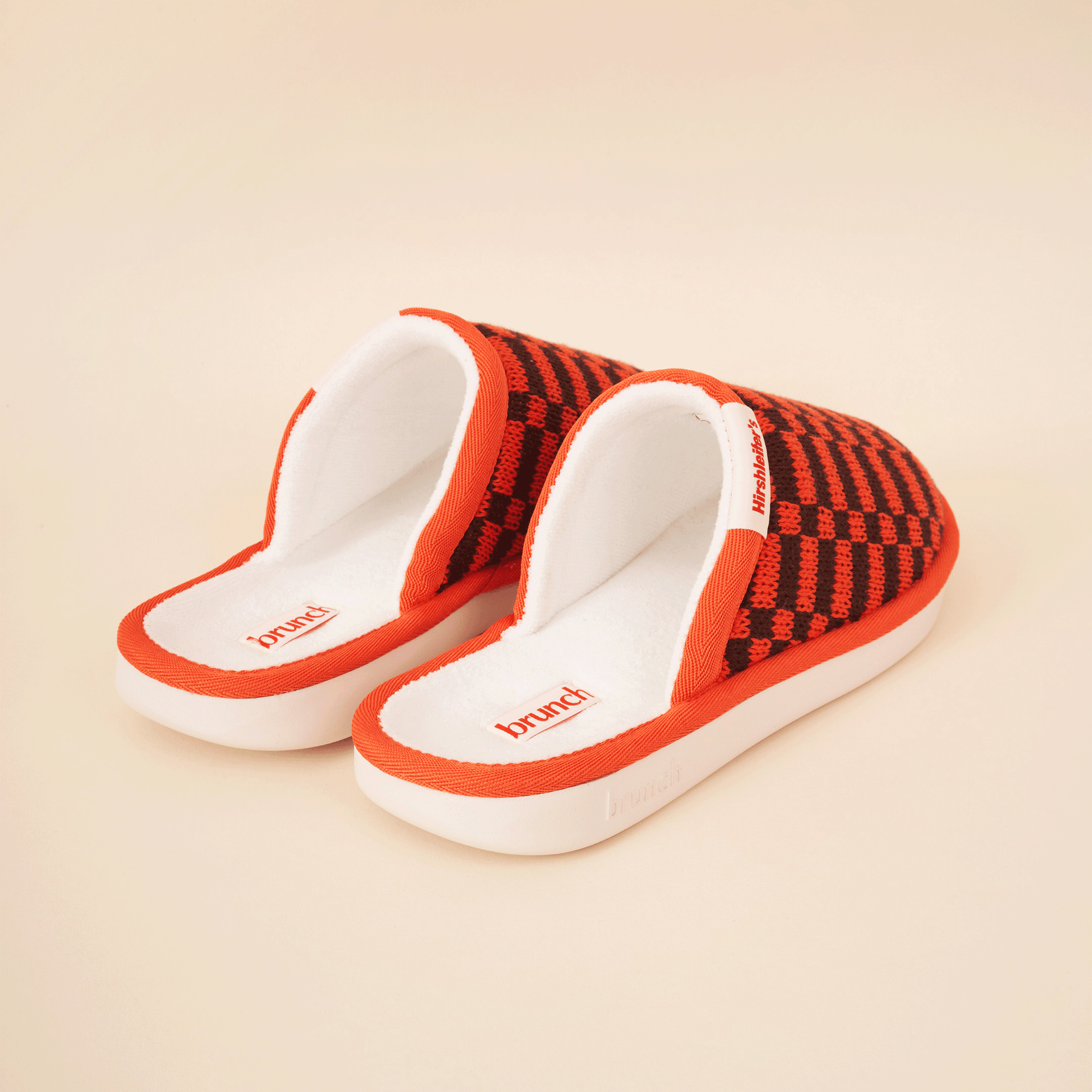Red-orange knit slide slippers with white terry insoles; 'brunch' printed on each insole.