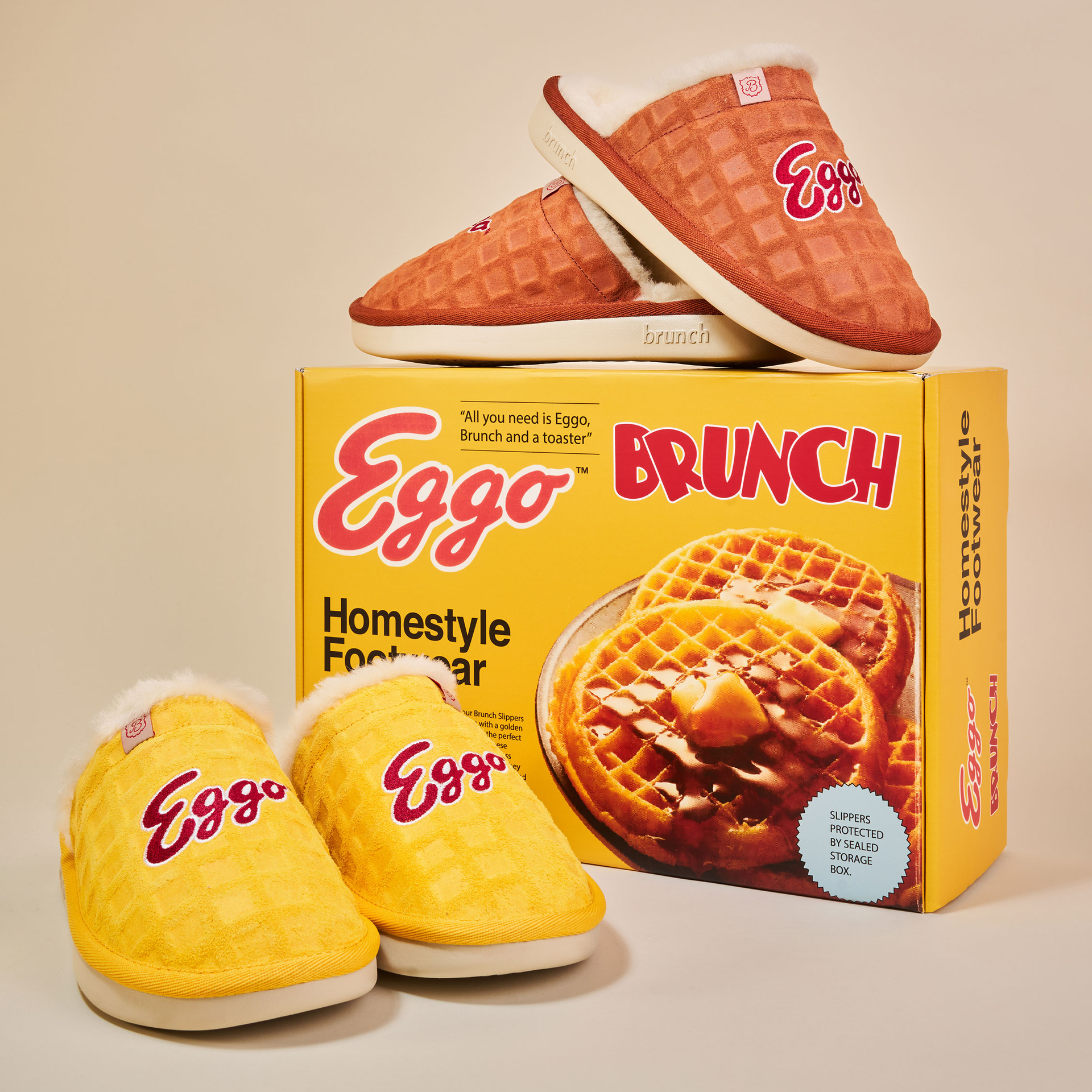 Yellow Eggo-branded waffle-texture slippers with faux fur lining beside an Eggo BRUNCH Homestyle Footwear box.