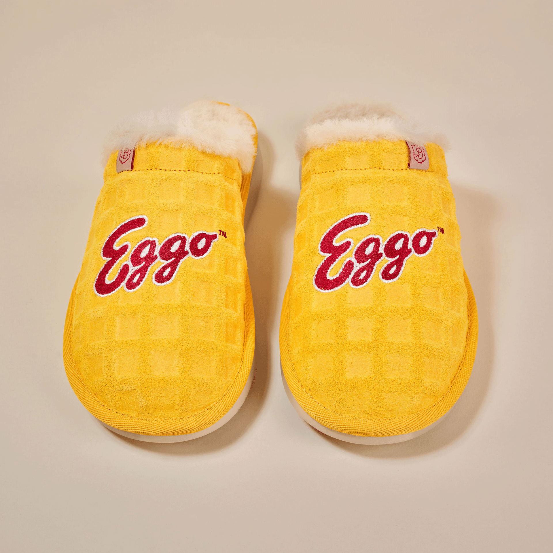 Yellow waffle-pattern Eggo slippers with white faux-fur lining, pair shown top-down