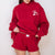 Person wearing a red sweatshirt and shorts set with a logo on a white background