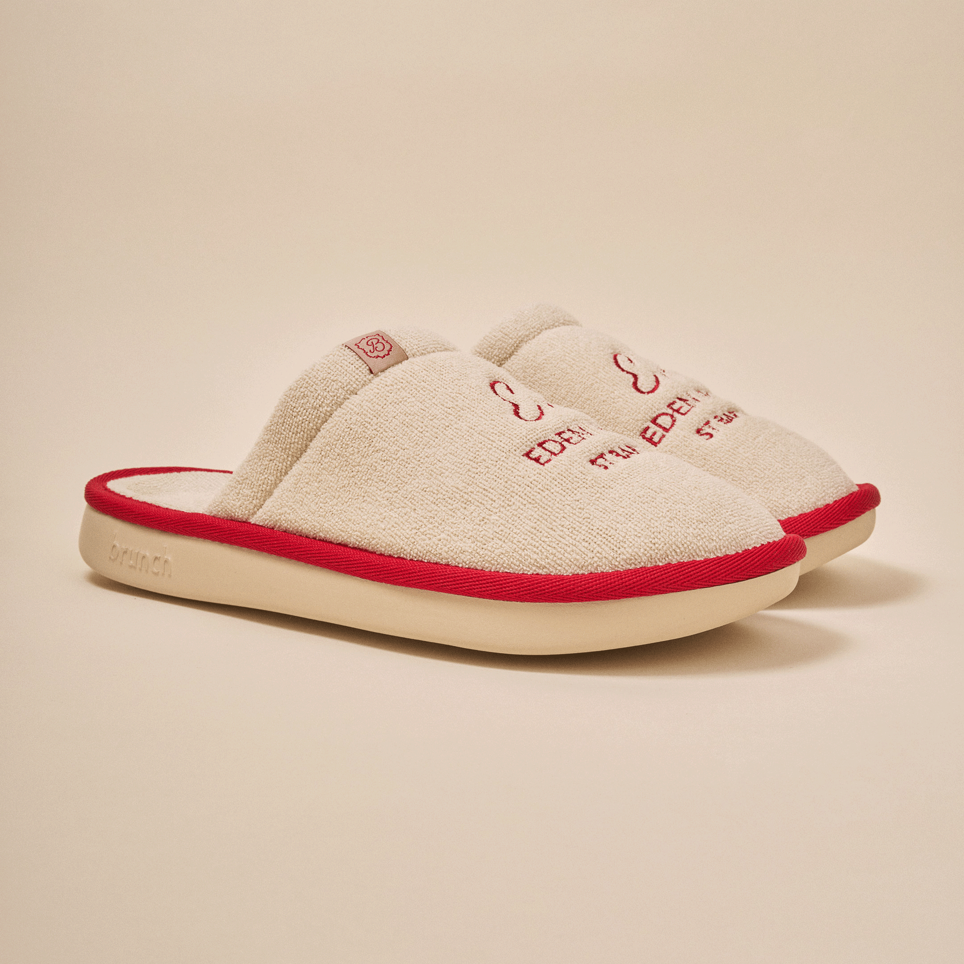 Beige terry cloth slip-on slippers with red piping, embroidered 'EDEN', B logo tab, and molded sole stamped 'brunch'.