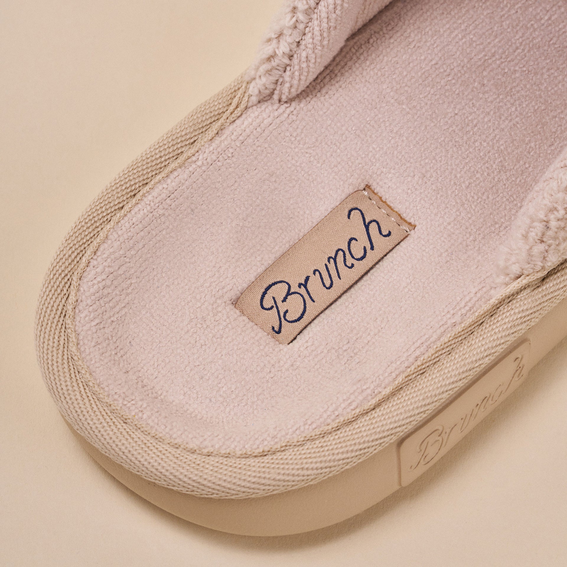 Beige slipper interior with fabric label reading Brunch stitched into the insole.