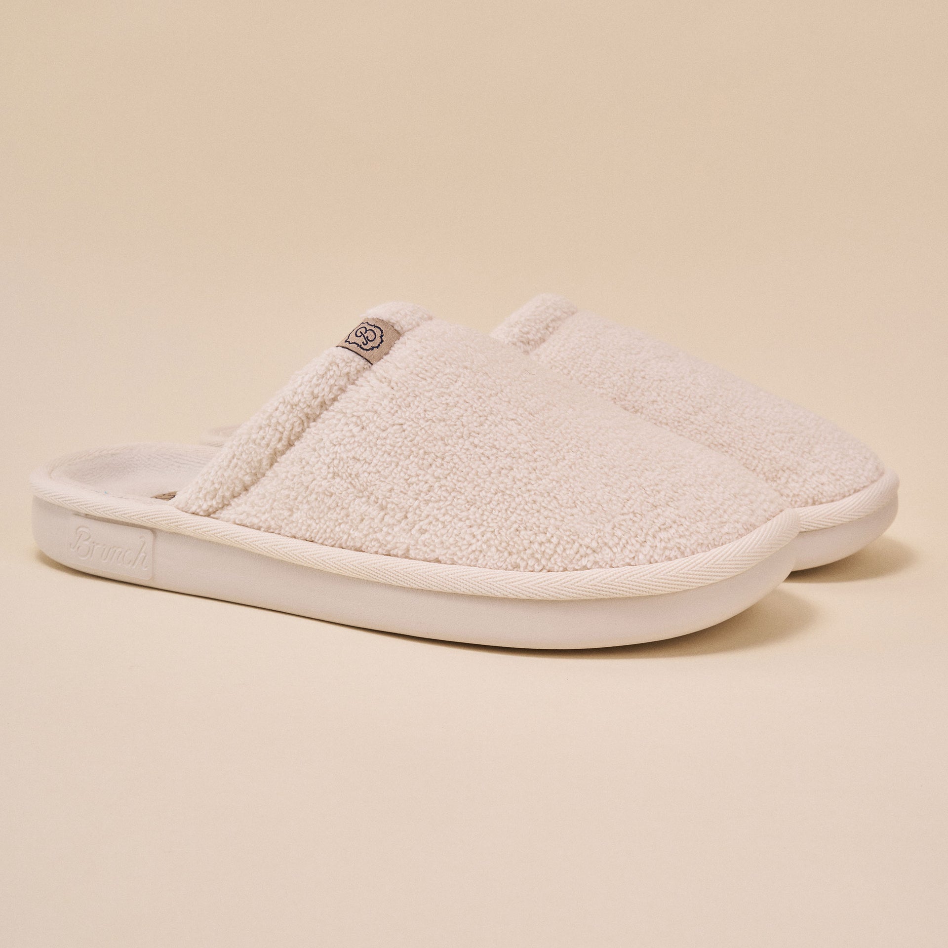 Cream sherpa slip-on slippers with "Brunch" embossed on sole