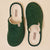 Pair of emerald green plush slip-on slippers with cream terry lining, top view, brand label Brunch visible