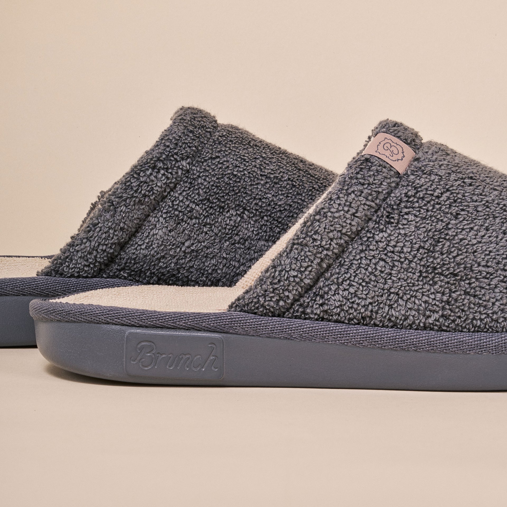 Grey terry-cloth slide slippers showing 'Brunch' embossed on the side of the sole.