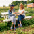 Two women laughing on a farm picnic bench, wearing navy slip-on shoes labeled AMBER WAVES FARM.