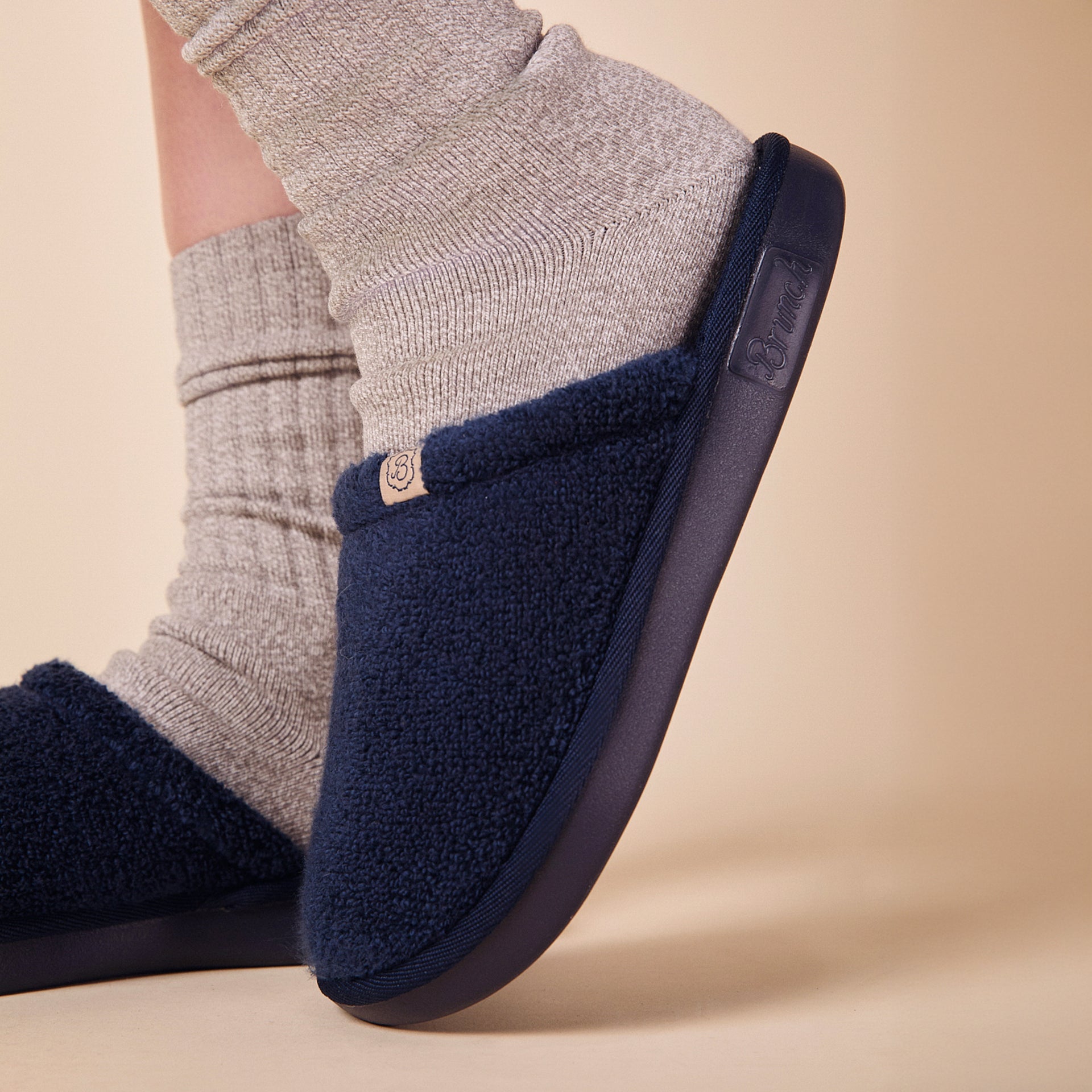 Navy sherpa slip-on slipper on foot, showing textured upper, molded sole, and gray ribbed socks