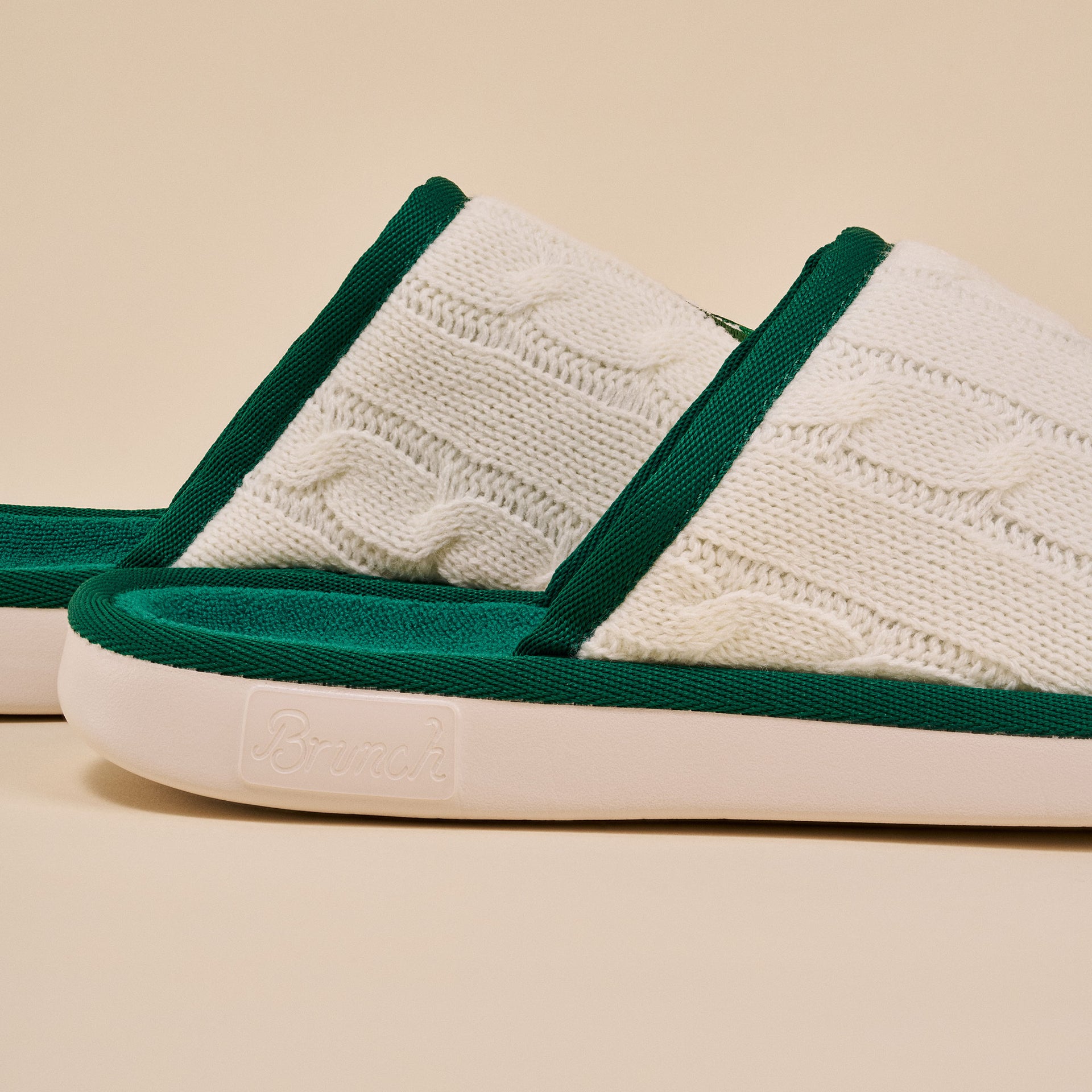 White cable-knit slippers with green trim, sole embossed 'Brunch'