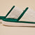 White cable-knit slippers with green trim, sole embossed 'Brunch'