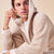 Man in beige hooded fleece robe, close-up three-quarter view, gazing upward