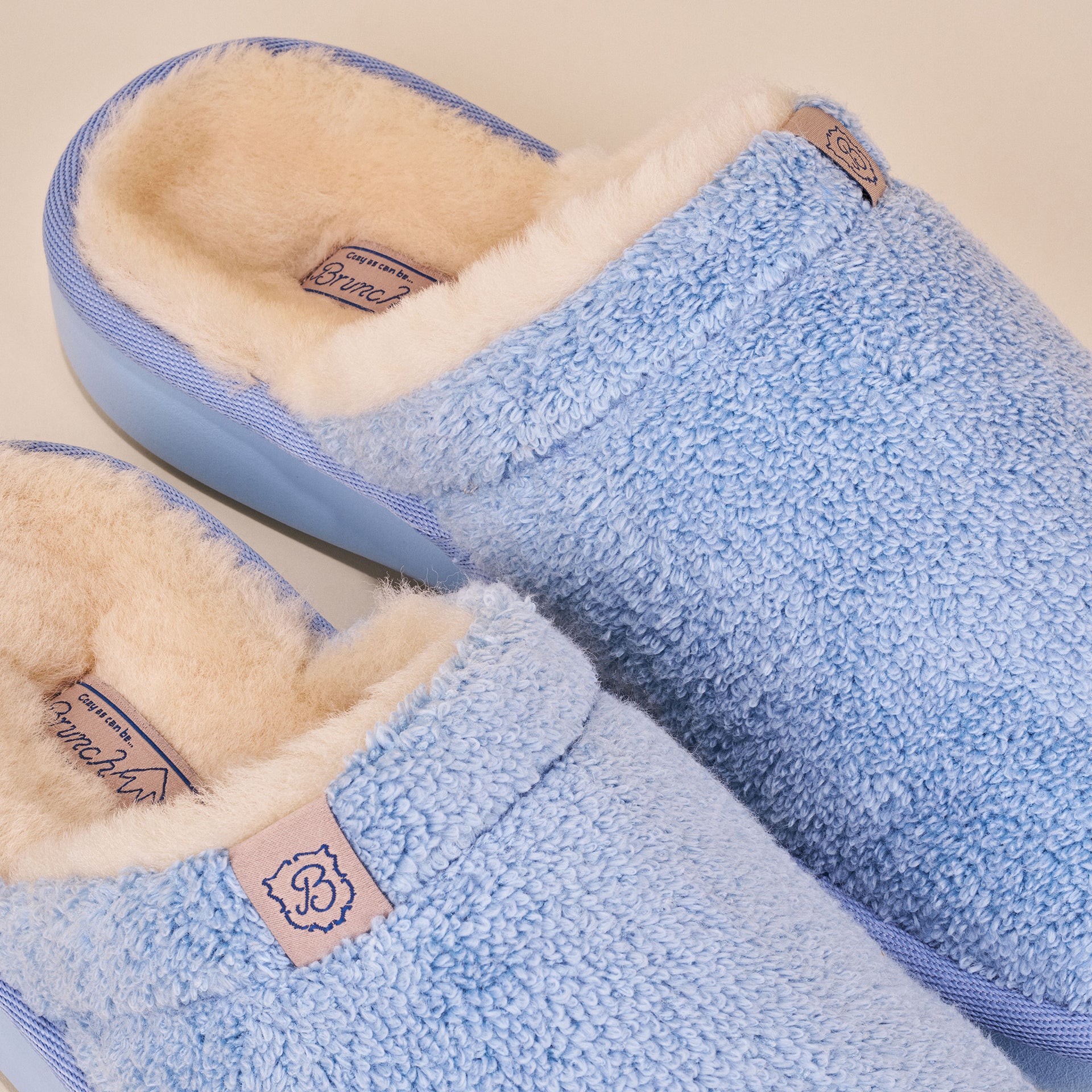 light blue terry slip-on slippers with cream shearling lining and 'B' monogram tag