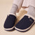 Navy slip-on slippers with cream faux-fur lining and Brunch embroidered on top, worn with gray socks.