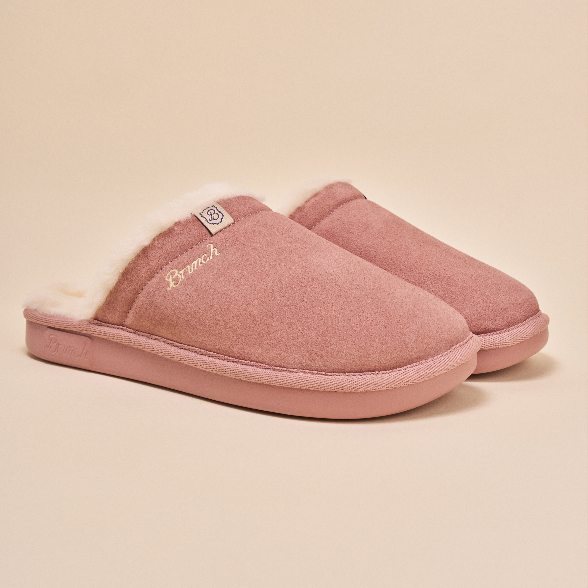 Pair of mauve suede slip-on slippers with cream faux-fur lining, 'Brunch' embroidered on side and small 'B' logo tab.