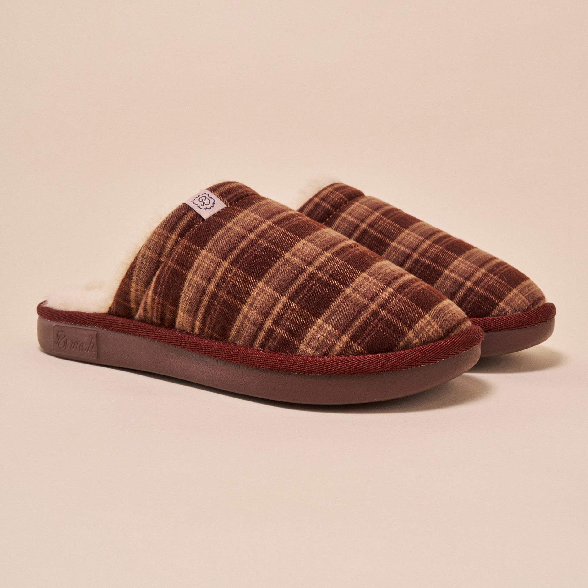 Brown plaid slip-on slippers with fleece shearling lining and small 'B' brand tag
