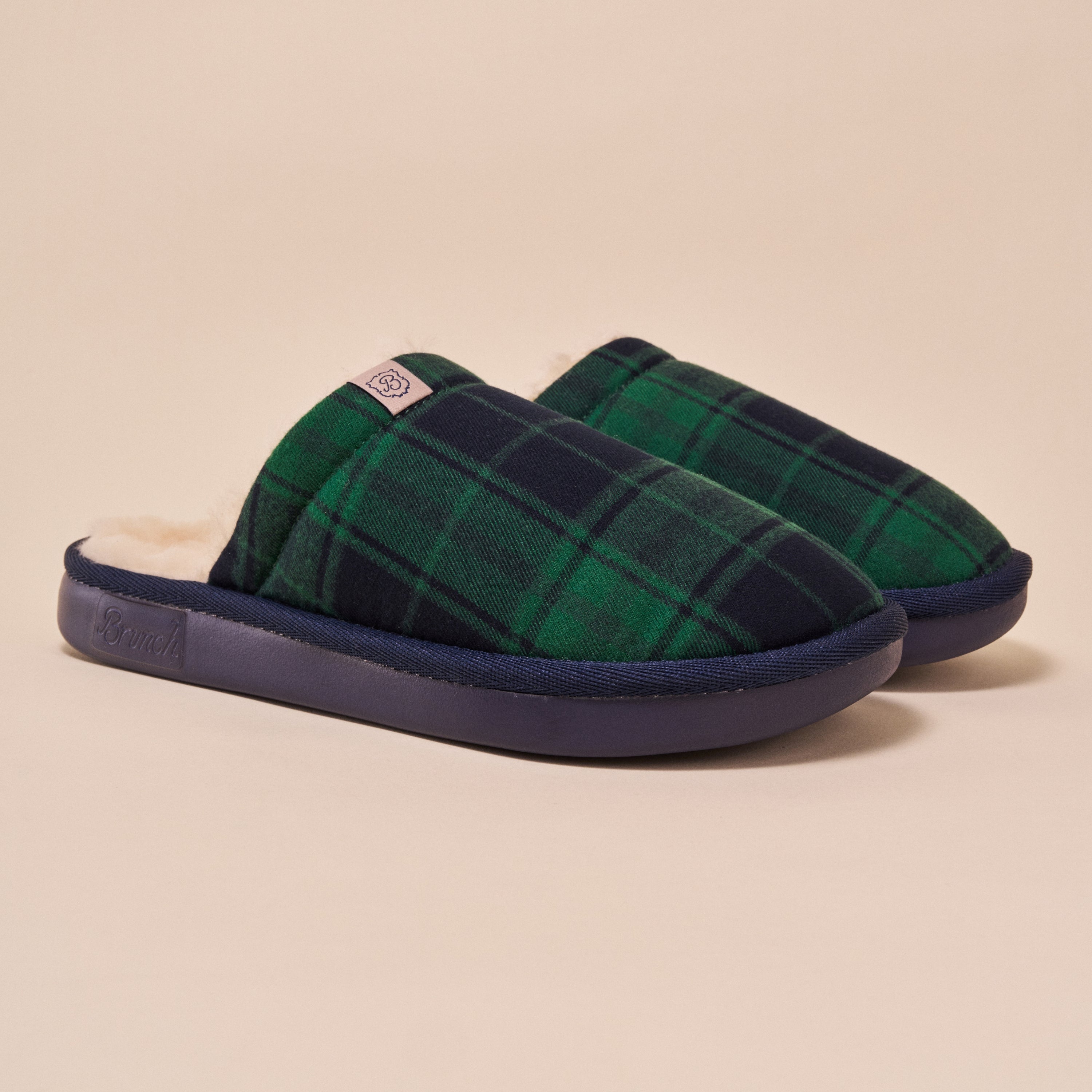 Green plaid slippers with navy soles on a beige background