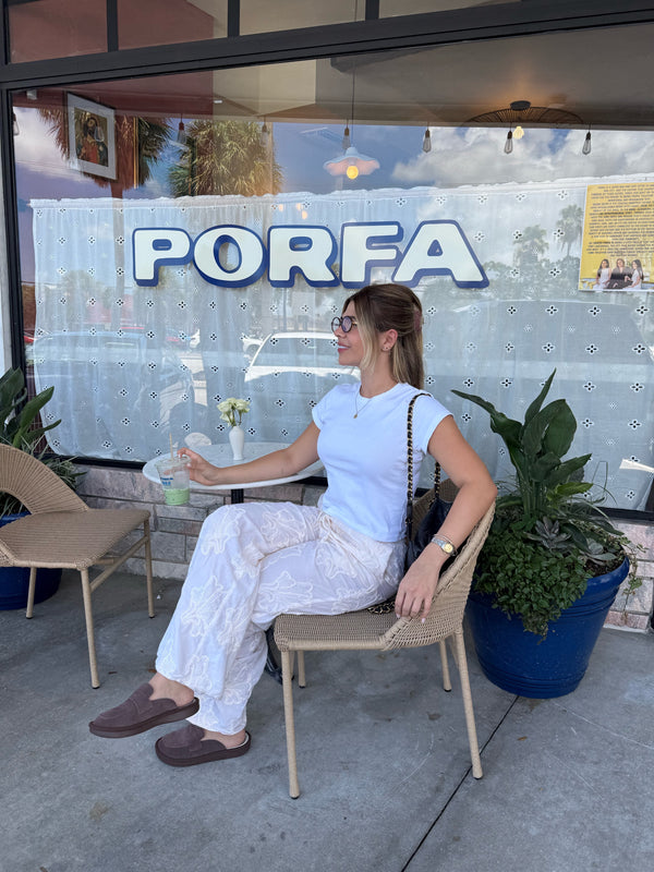 Side view of sandstone suede Loafer on seated model showcasing slip-on silhouette and low-profile outsole outside a cafe with PORFA sign
