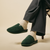 Pair of moss-green suede slip-on slippers on a wooden surface