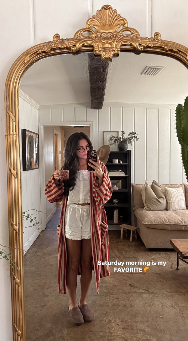 Mirror selfie: woman in white pajama set and red-striped robe holding mug in living room Text: Saturday morning is my FAVORITE