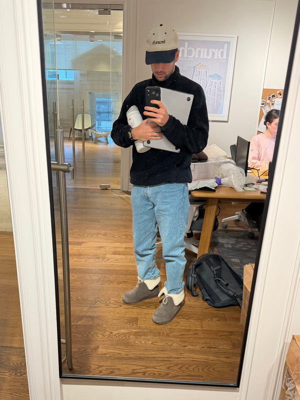 Full-length mirror view of Apres Boot in camel nubuck with folded shearling cuff, jeans, and office background
