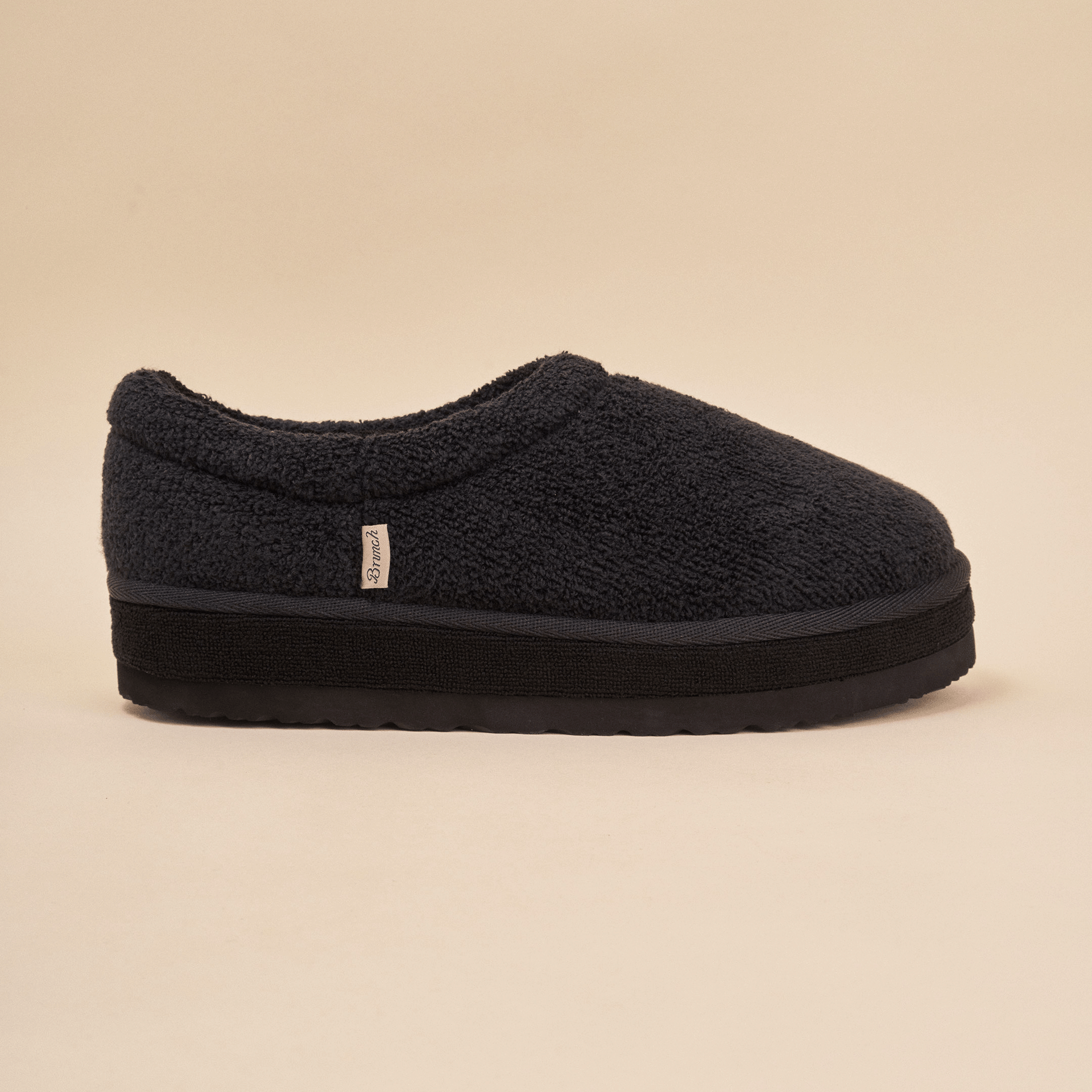 Black sherpa slip-on slipper with thick platform sole and small fabric side tag