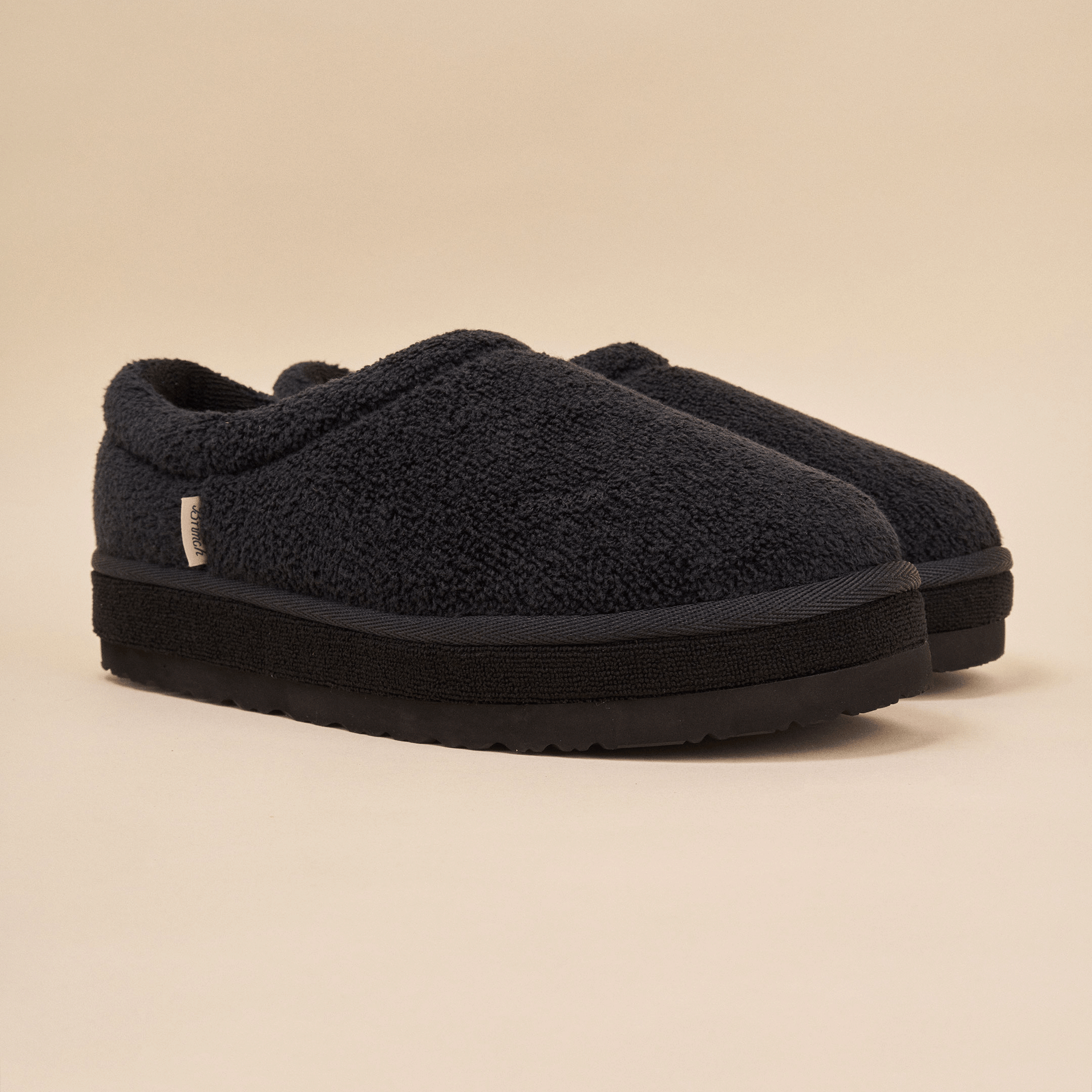 Black sherpa fleece slip-on slippers with cushioned thick sole and small side fabric tag