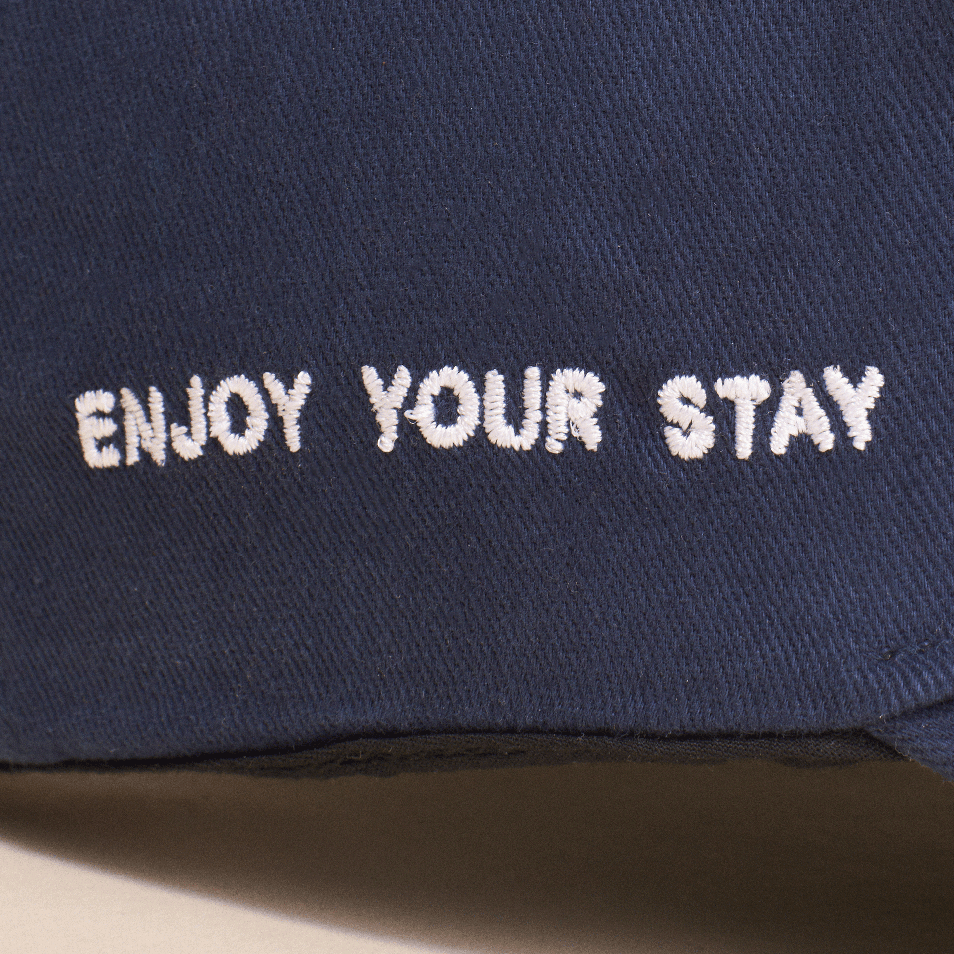 Navy fabric with white embroidered text 'ENJOY YOUR STAY'