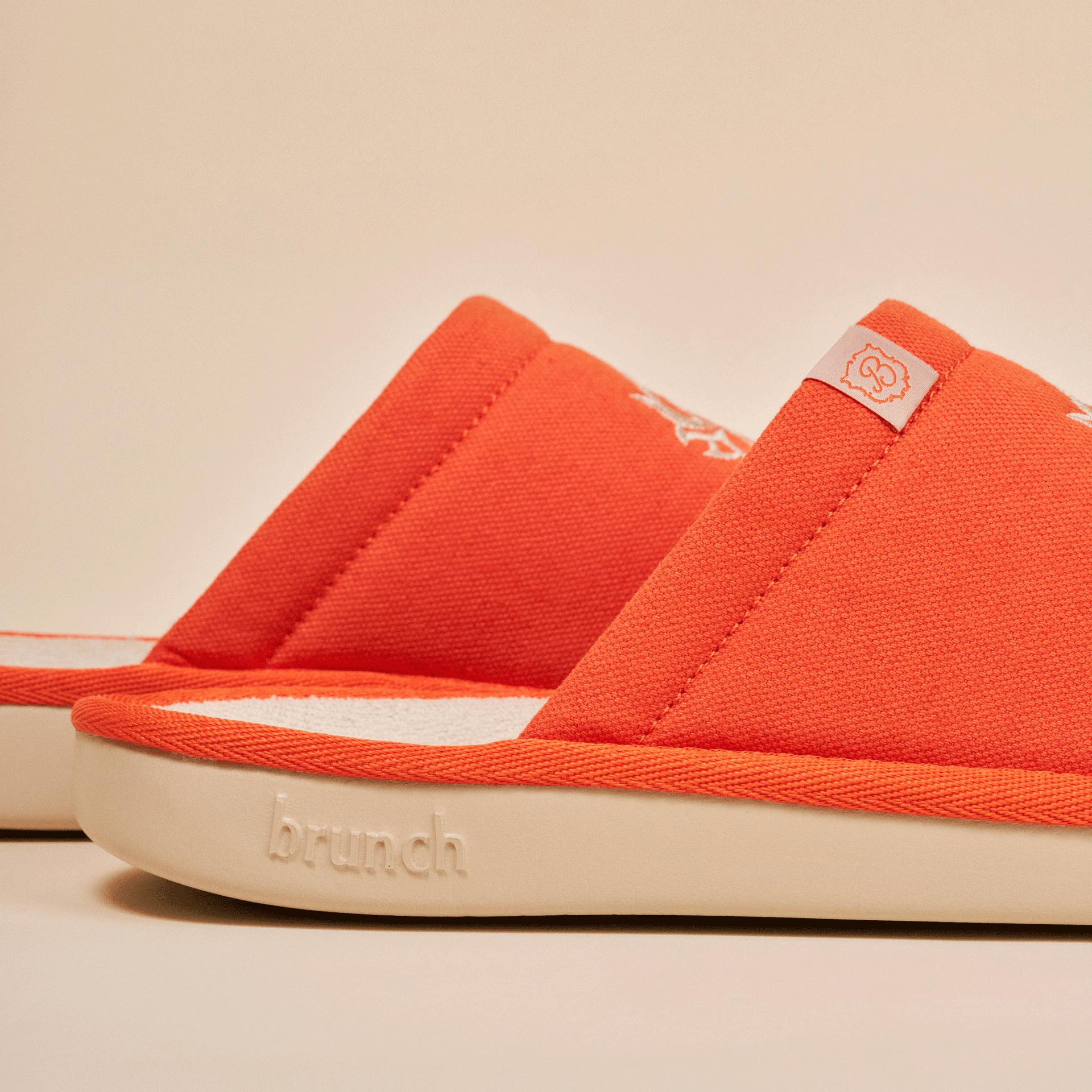 Close-up of orange slide slippers with brunch embossed on the cream sole