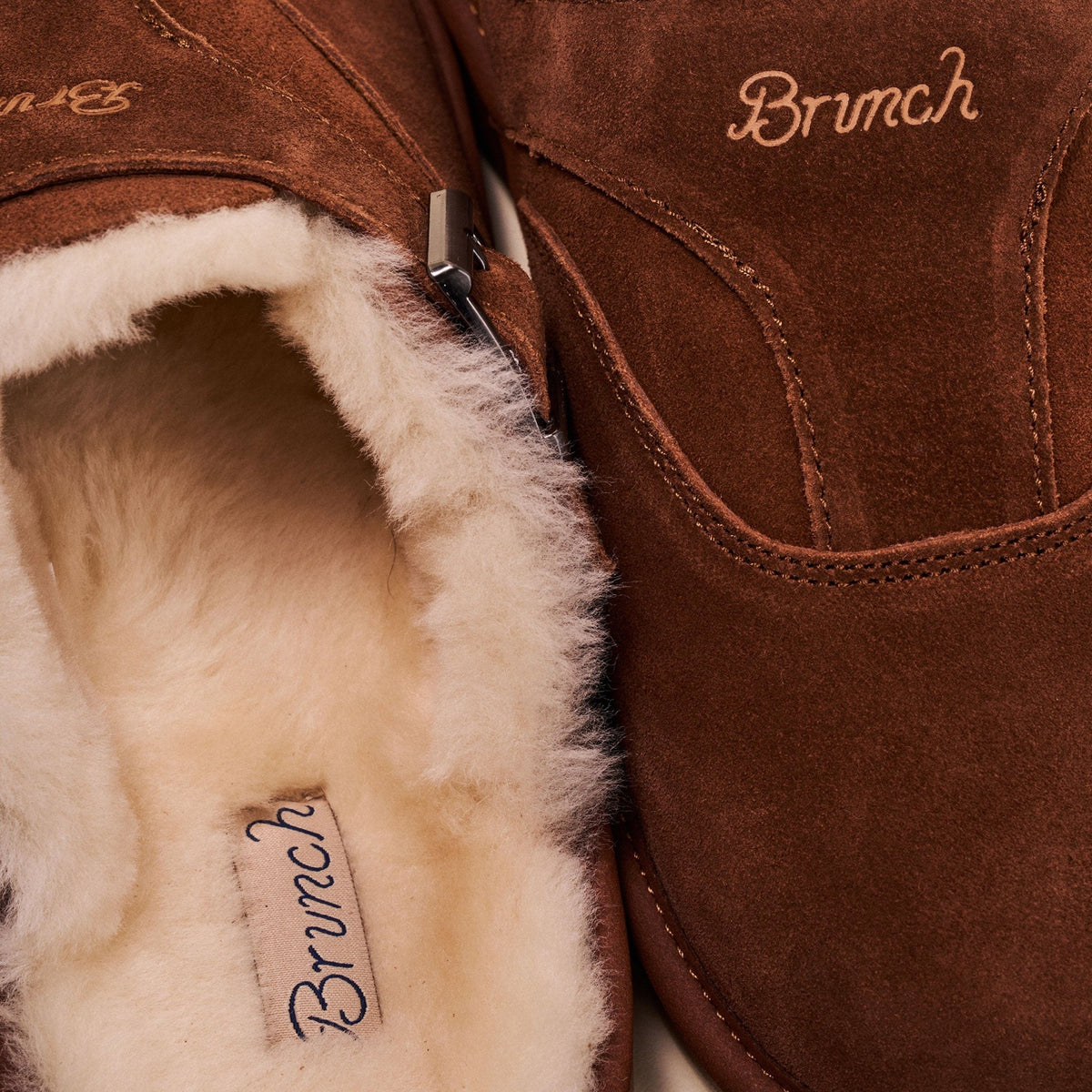 Close-up of Amour Shearling slipper showcasing horse brown suede upper, cream shearling lining, and visible Brunch logo