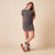 Model standing with crossed legs wearing camel nubuck Apres boots with folded shearling cuff and platform sole on beige background